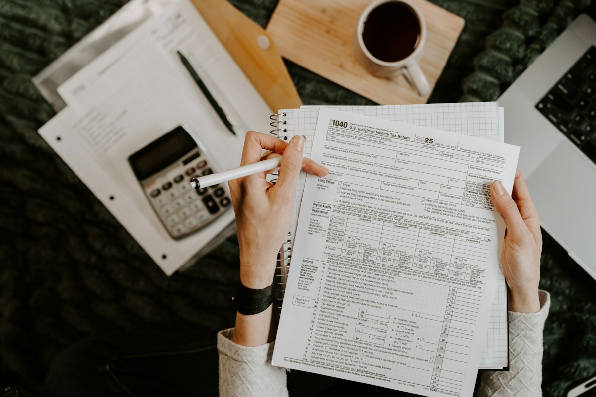 Personne examinant des documents avec une calculatrice et un ordinateur