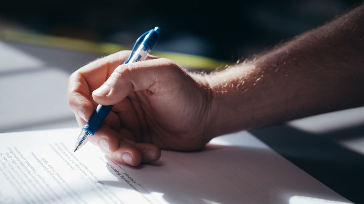 Main signant un document avec un stylo