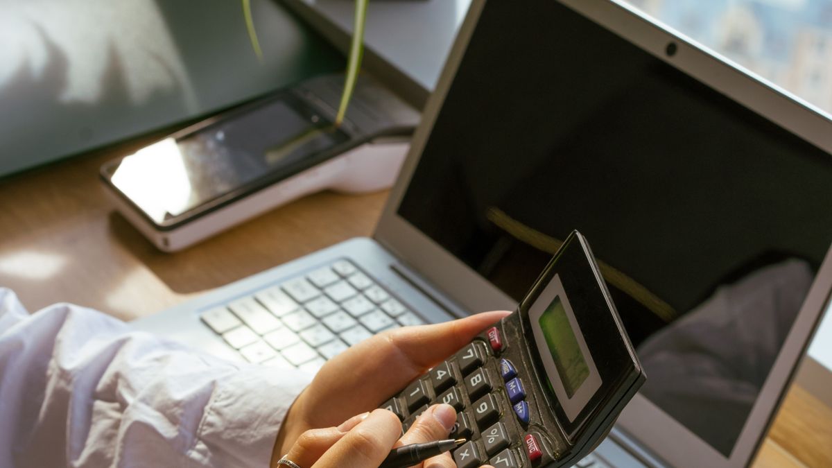 Personne utilisant une calculatrice à côté d'un ordinateur