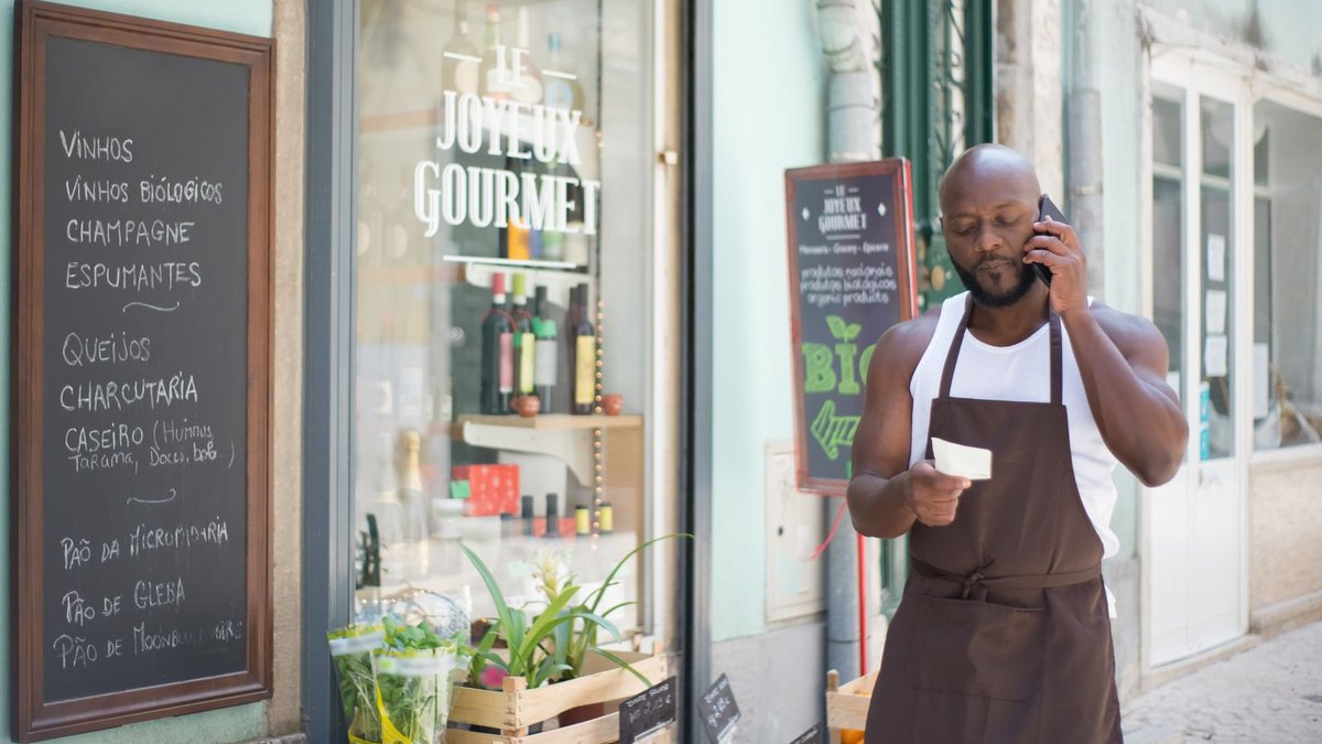 Commerçant au téléphone devant son épicerie à Lisbonne
